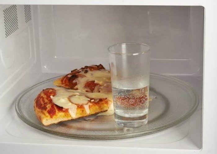 Пицца и стакан воды в микроволновке